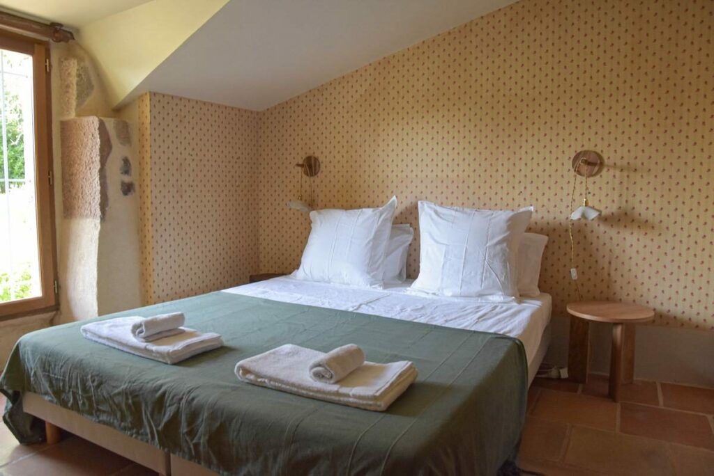 Chambre mansardée au papier peint fleuri, avec un lit double