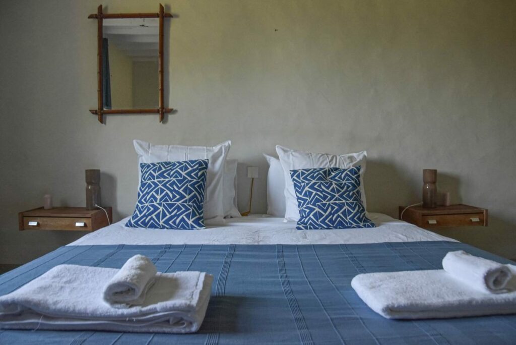 Chambre avec lit double, plaid bleu et miroir en bambou