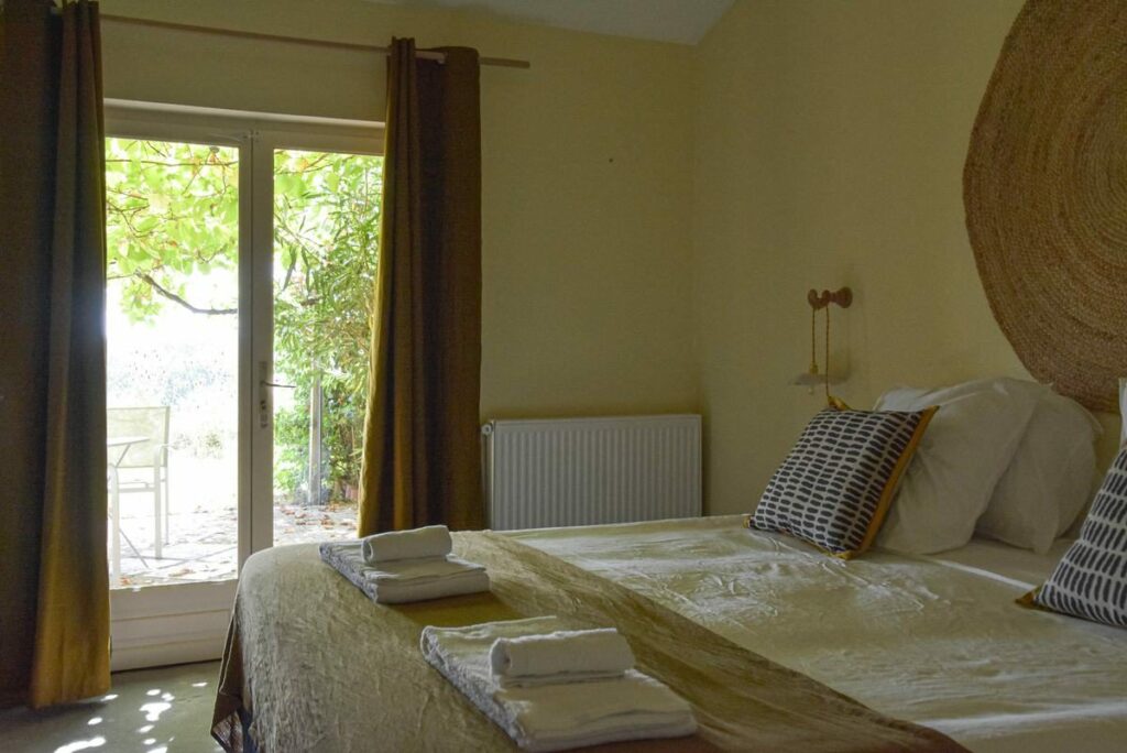 Chambre lumineuse avec porte-fenêtre ouverte sur une terrasse