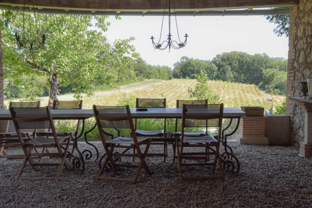 Le préau : une grande table en fer forgé face aux prés et aux collines boisées