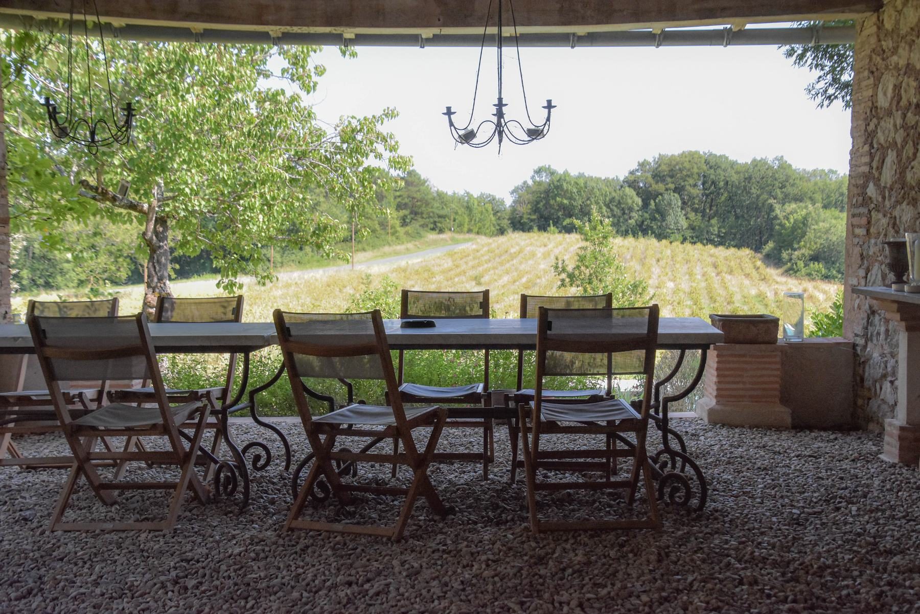 Le préau : une grande table en fer forgé face aux prés et aux collines boisées