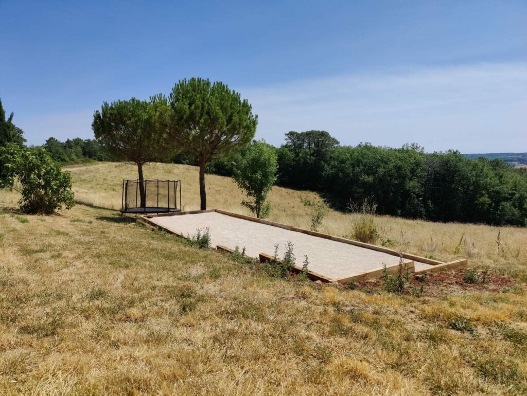 Le terrain de pétanque et le trampoline, entourés de prés et de pins parasols