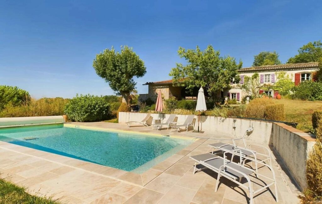 La piscine chauffée et ses chaises longues, avec la maison en arrière-plan