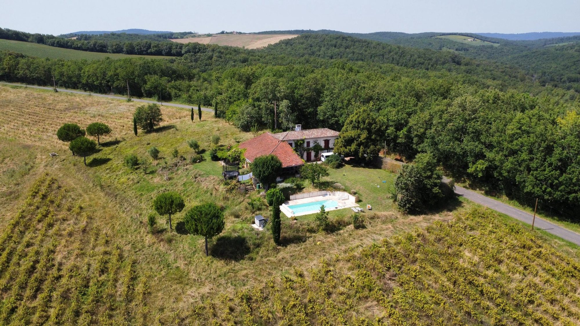 Maison Littré vue du ciel, entourée de prés et de collines boisées, à Castelnau-de-Montmiral dans le Tarn